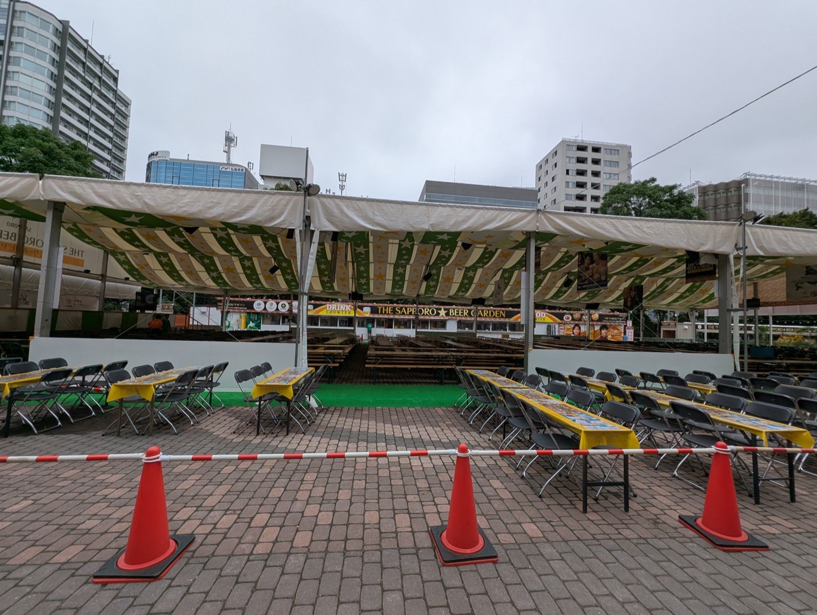 星柄の大型テント内に整然と並ぶビアガーデンのテーブル・ベンチ席と、DRINK・FOOD COUNTERの案内看板