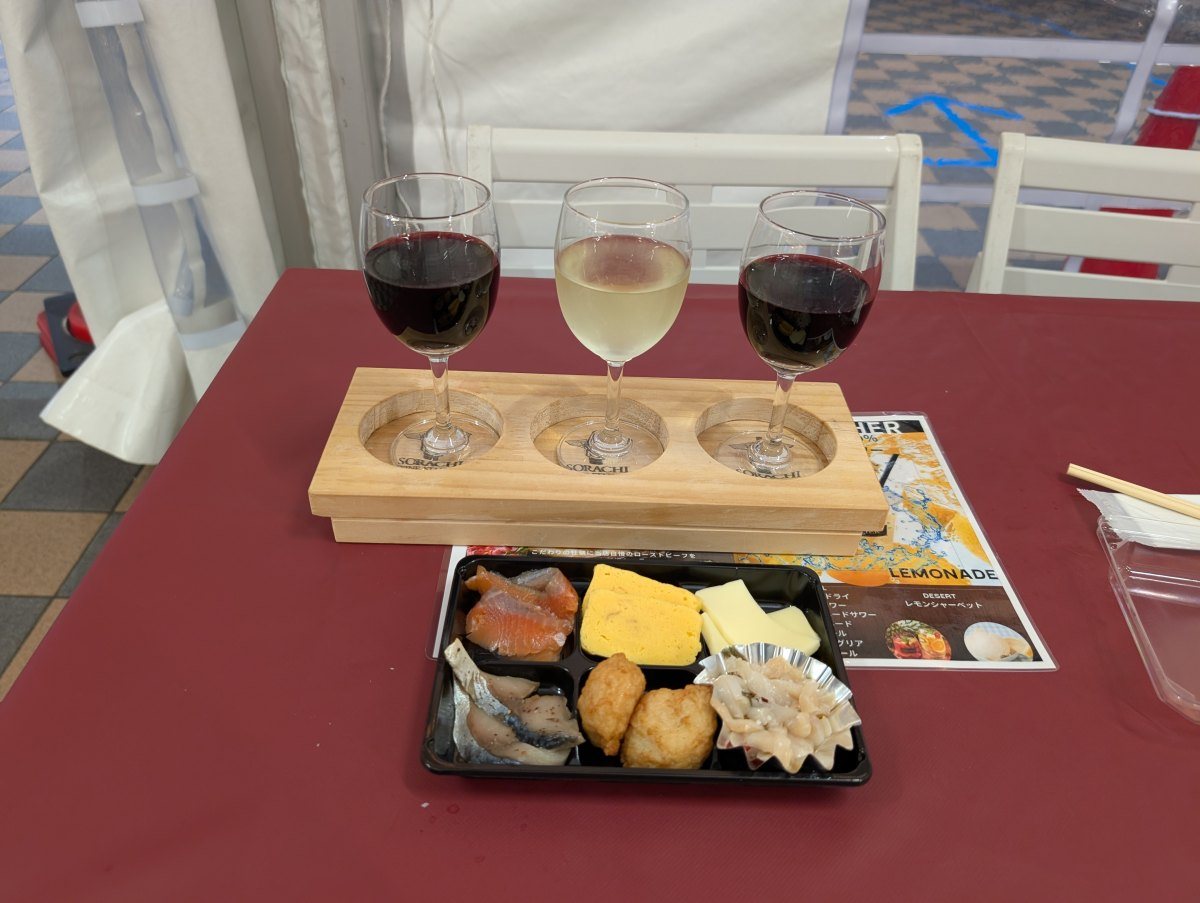 ワイン3種飲み比べとおつまみセットを並べたところ。テーブルは赤いクロスがかかっています(2026年9月19日 撮影)