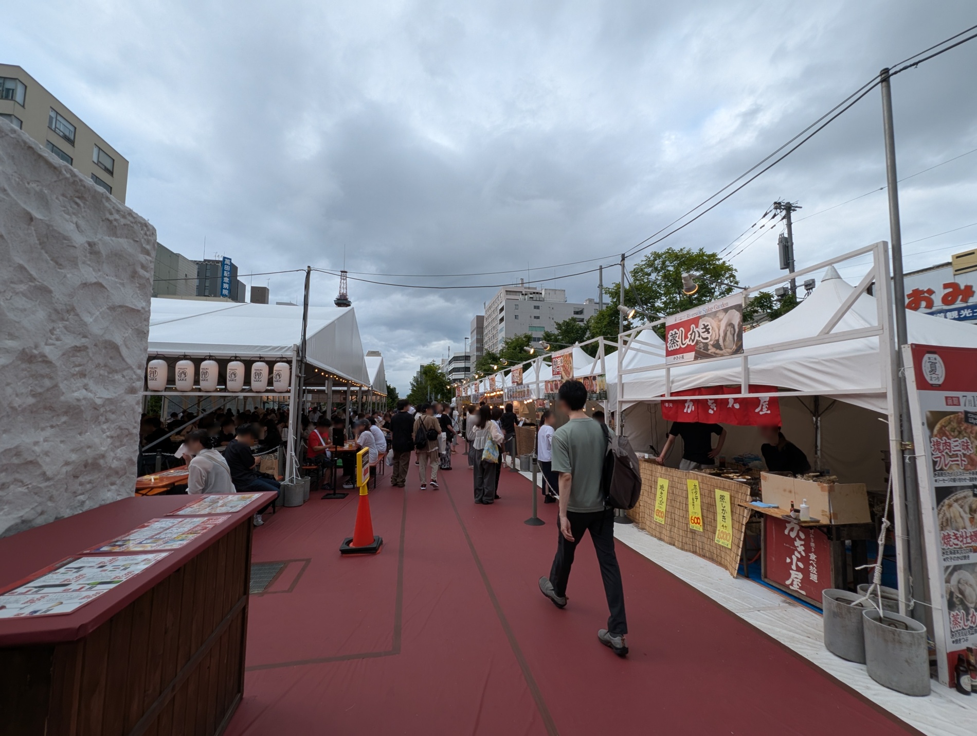 かき小屋の屋台外観。「蒸しかき」の看板と黄色い価格札が並びます